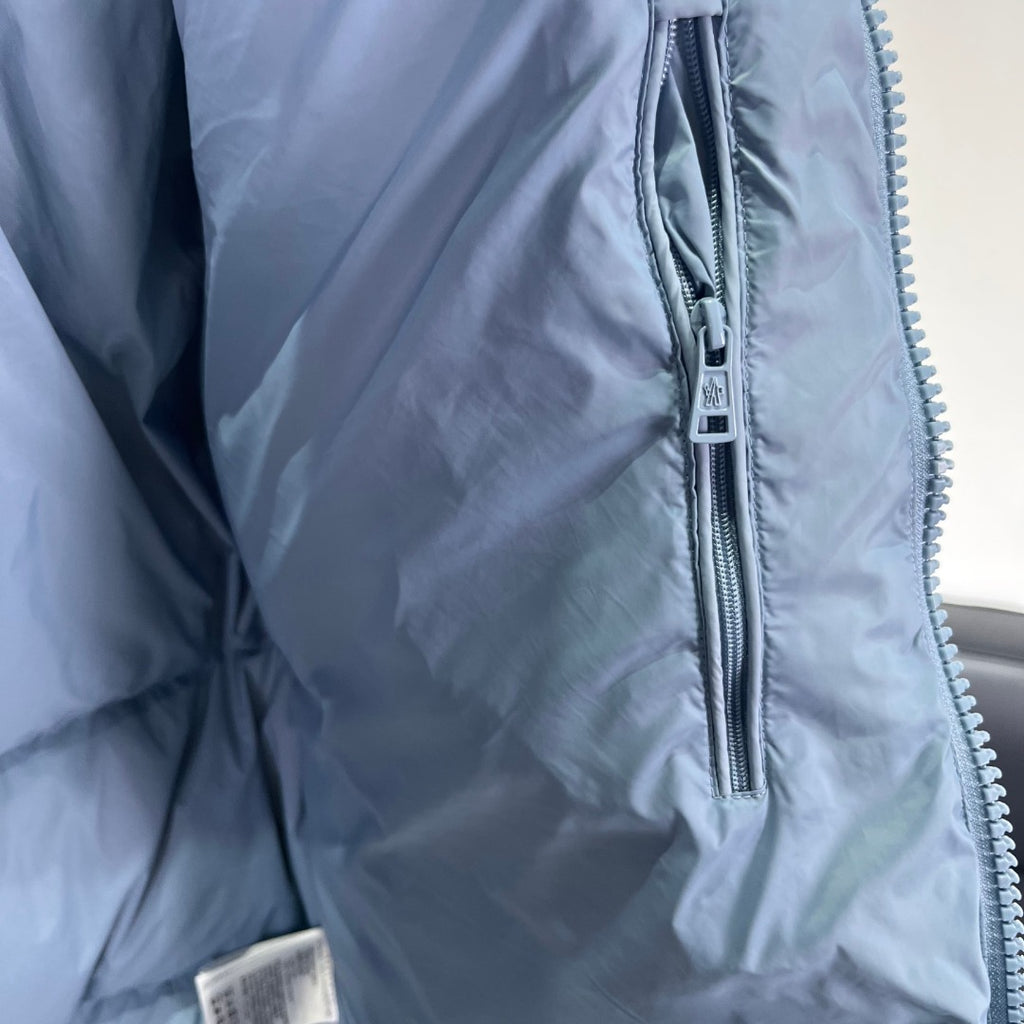 Light blue puffer jacket side close-up with metal front zipper