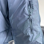 Light blue puffer jacket side close-up with metal front zipper