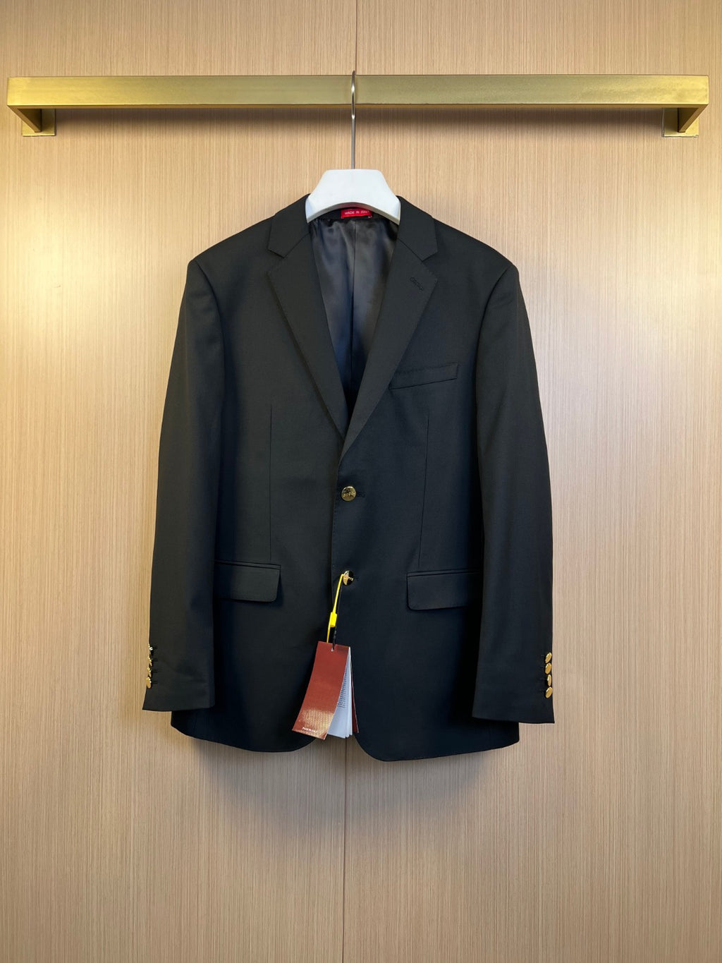 Dark blazer with notch lapels, flap pockets, and gold-tone button detailing