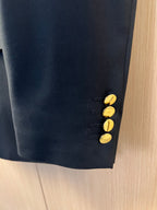 Dark trousers with gold-tone buttons at the waistband