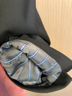 Dark long coat sleeve cuff with blue trim and stitched detail