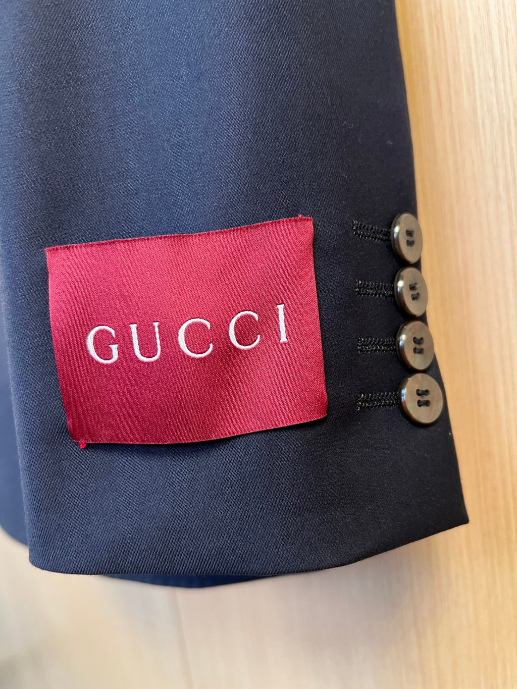 Navy blazer sleeve cuff with Gucci label and gold-tone button details