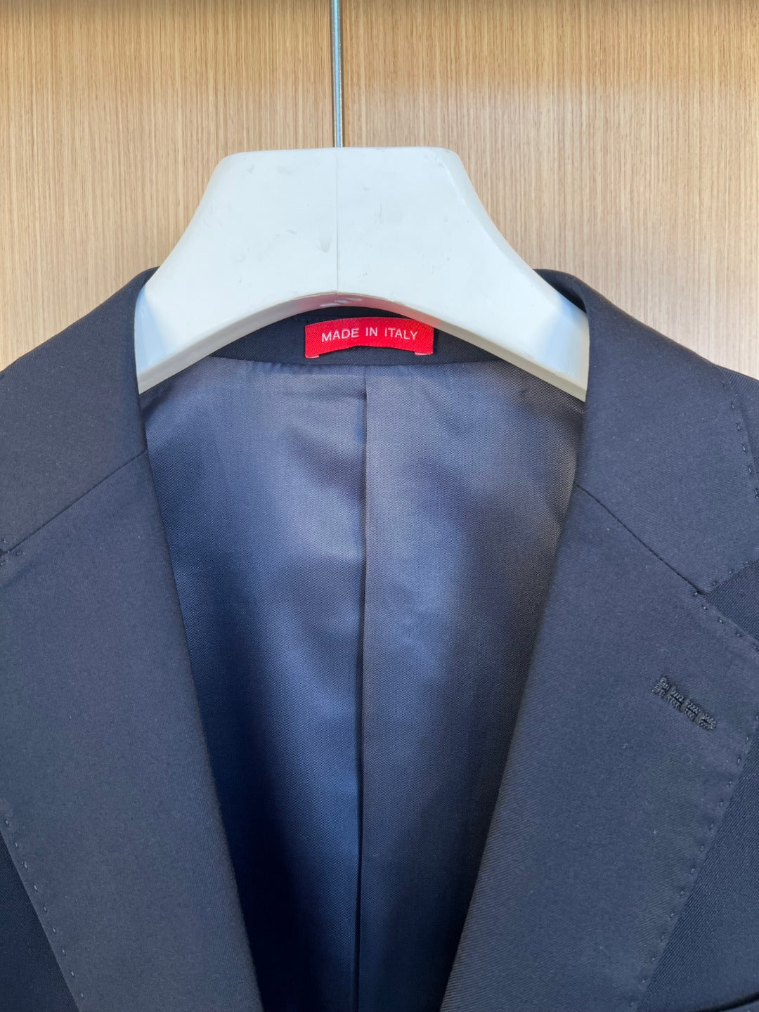 Navy suit jacket with hang tag and 'Made in Italy' label at the collar