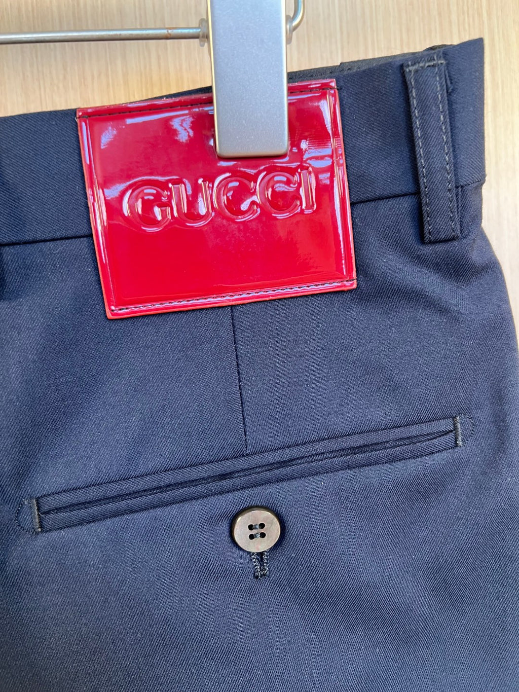 Dark navy pants front close-up with button and red logo hang tag