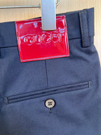 Dark navy pants front close-up with button and red logo hang tag