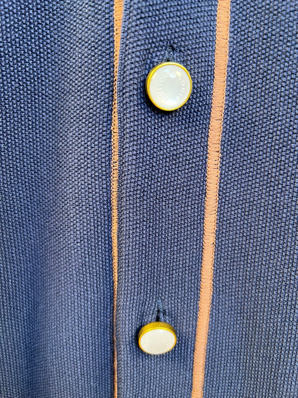 Navy knit polo shirt with tan-and-coral trim and gold button accents
