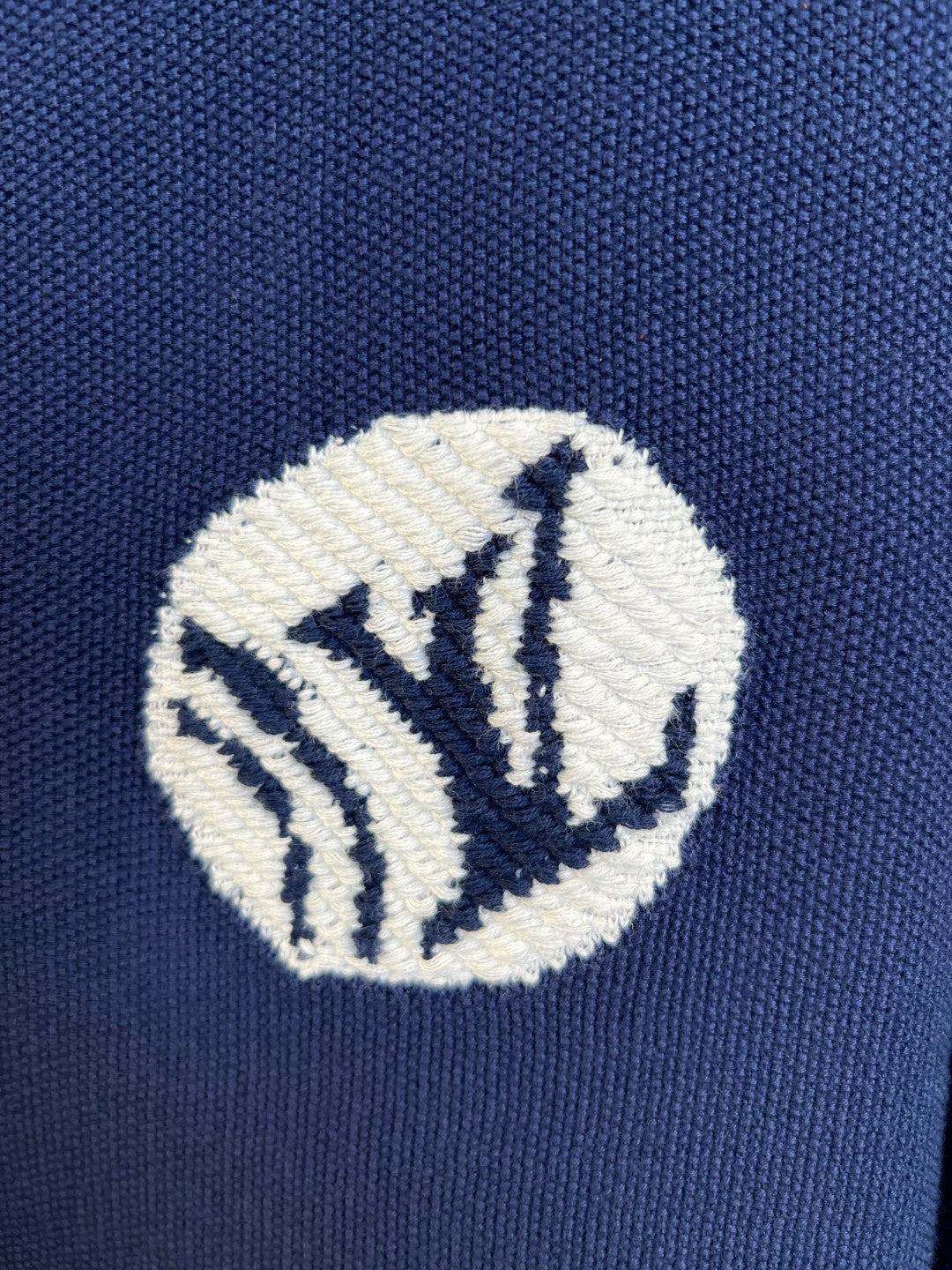 Embroidered crest patch on navy knit polo shirt