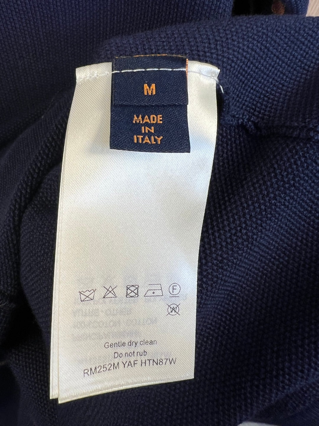 Care and size label on navy knit polo shirt marked "M" made in Italy