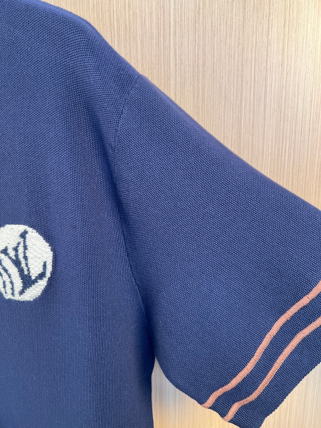 Navy knit polo shirt sleeve with embroidered crest logo
