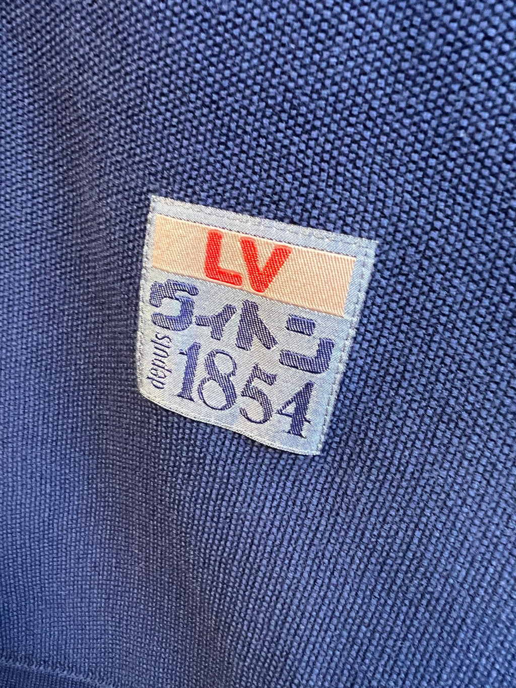 Inner size label on navy knit polo shirt with LV markings