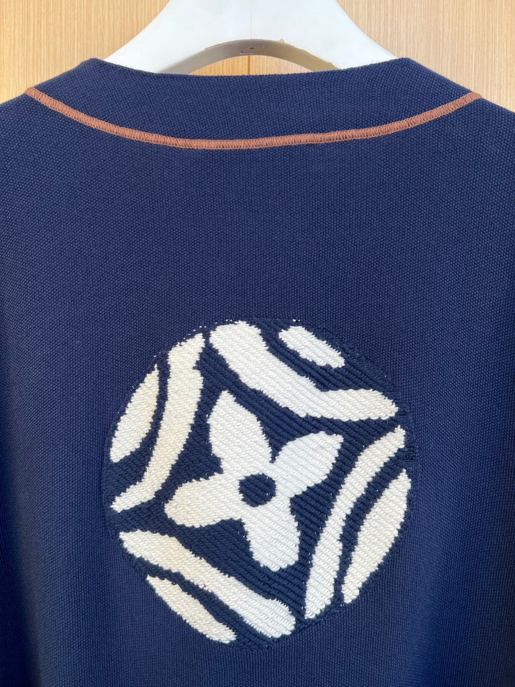 Large embroidered crest graphic on back of navy knit polo shirt