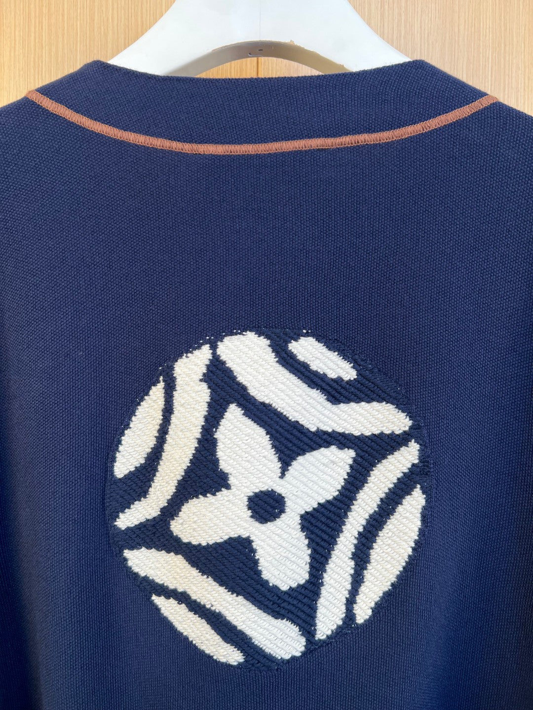 Large embroidered crest graphic on back of navy knit polo shirt