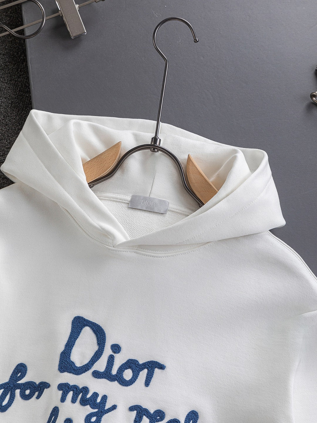 White Dior hoodie with hood and front pocket detail on hanger