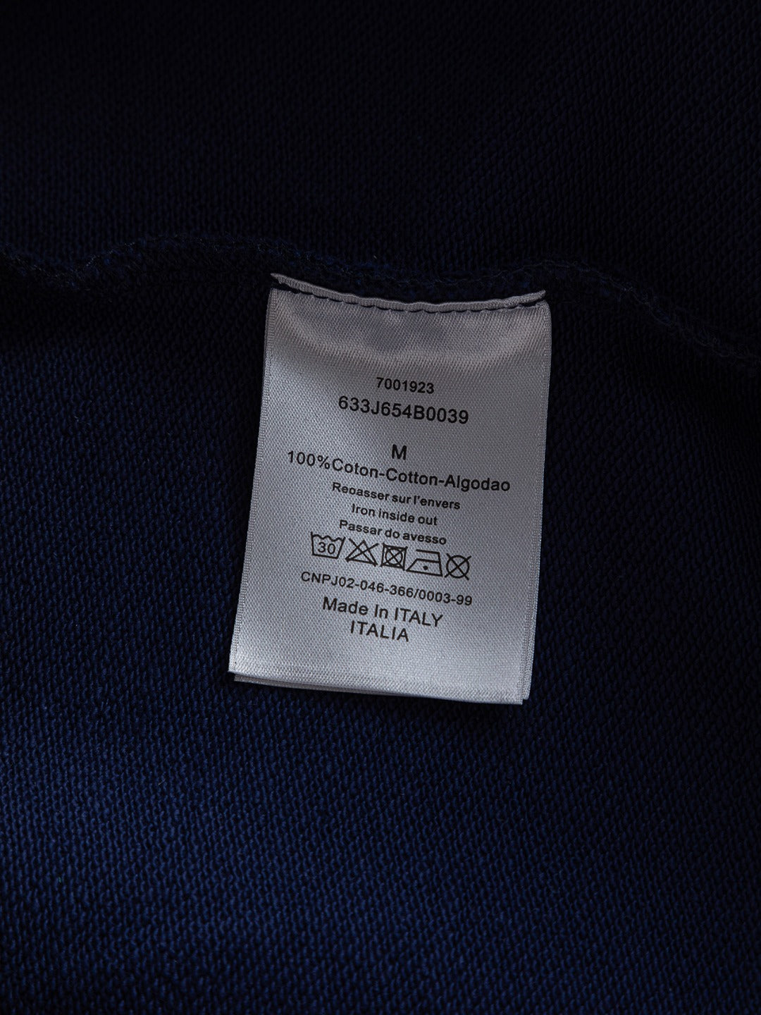 Dior long garment care label on dark fabric, 100% cotton