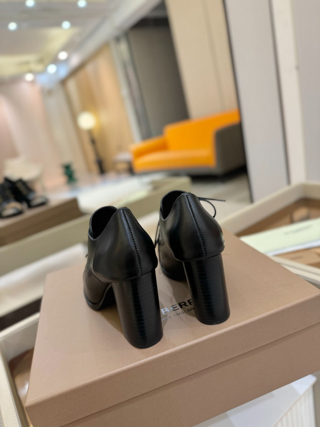 Black leather lace-up high-heel shoes, rear view on shoebox