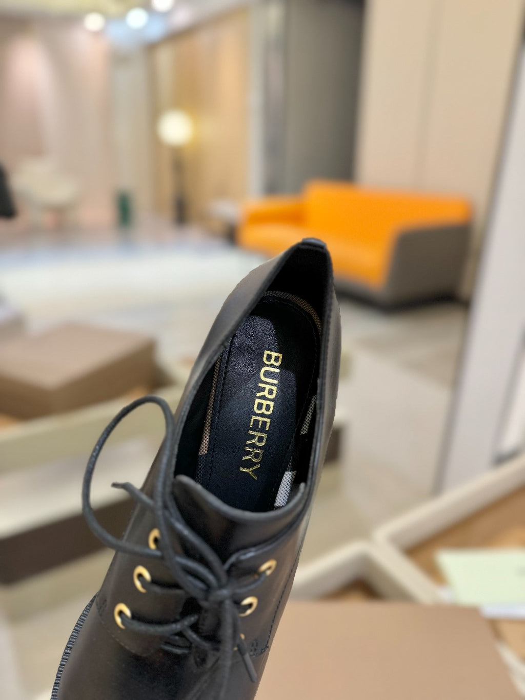 Black Burberry lace-up shoe with "BURBERRY" text on inner lining