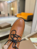 Burberry lace-up shoe close-up, tan leather with black laces and beige collar.