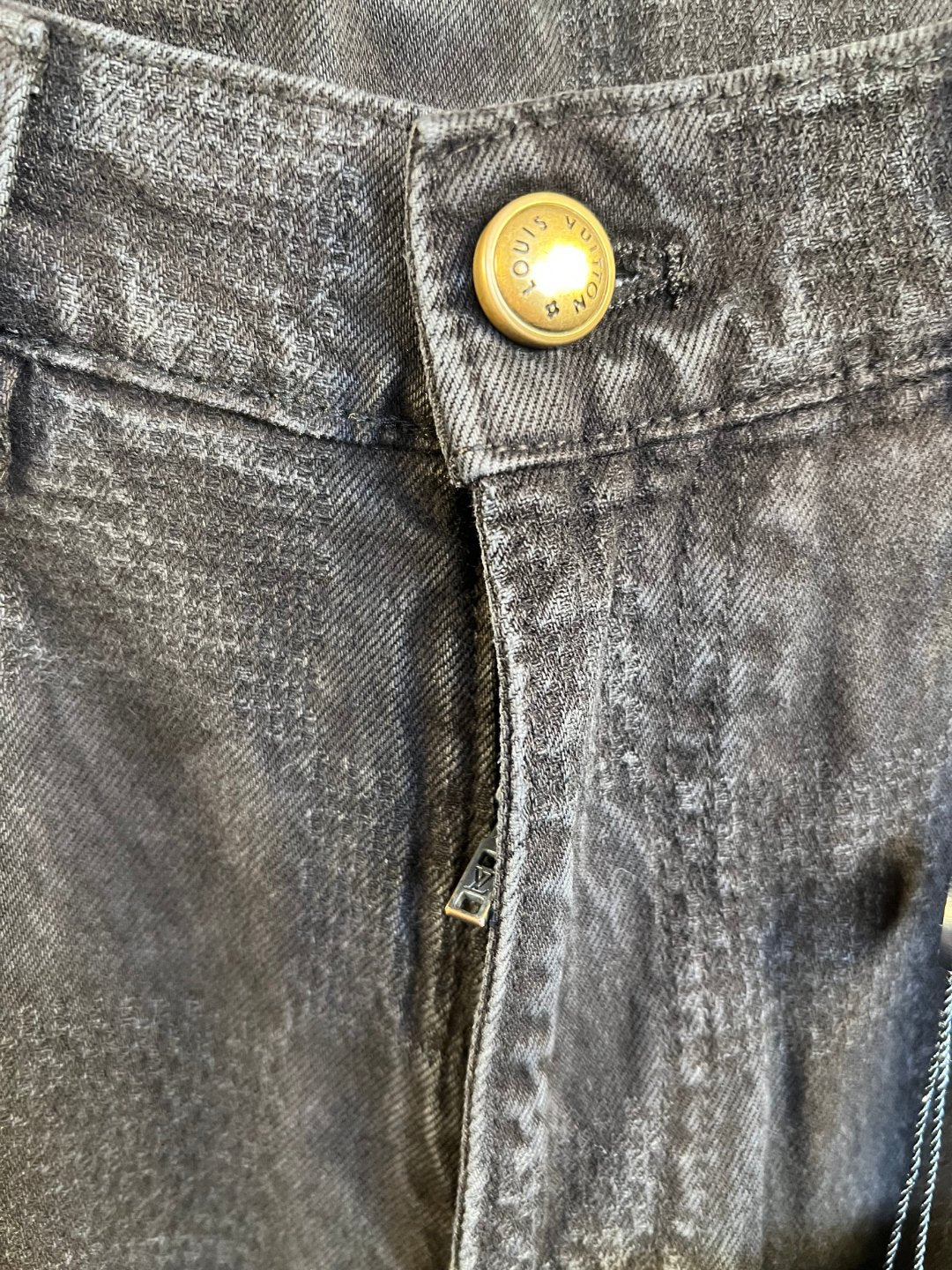 Dark denim jeans close-up of front button and waistband seam