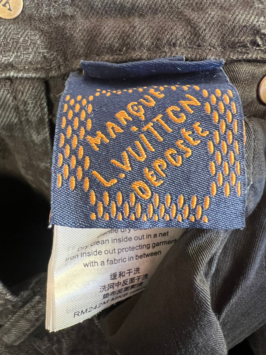 Dark denim jeans fabric care label with “Louis Vuitton” text