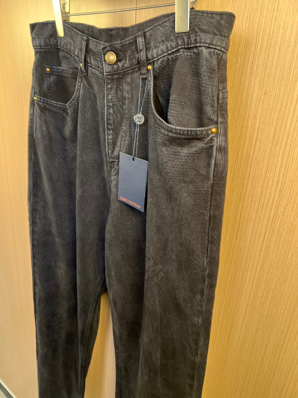 Dark denim jeans on hanger with front pockets and button details