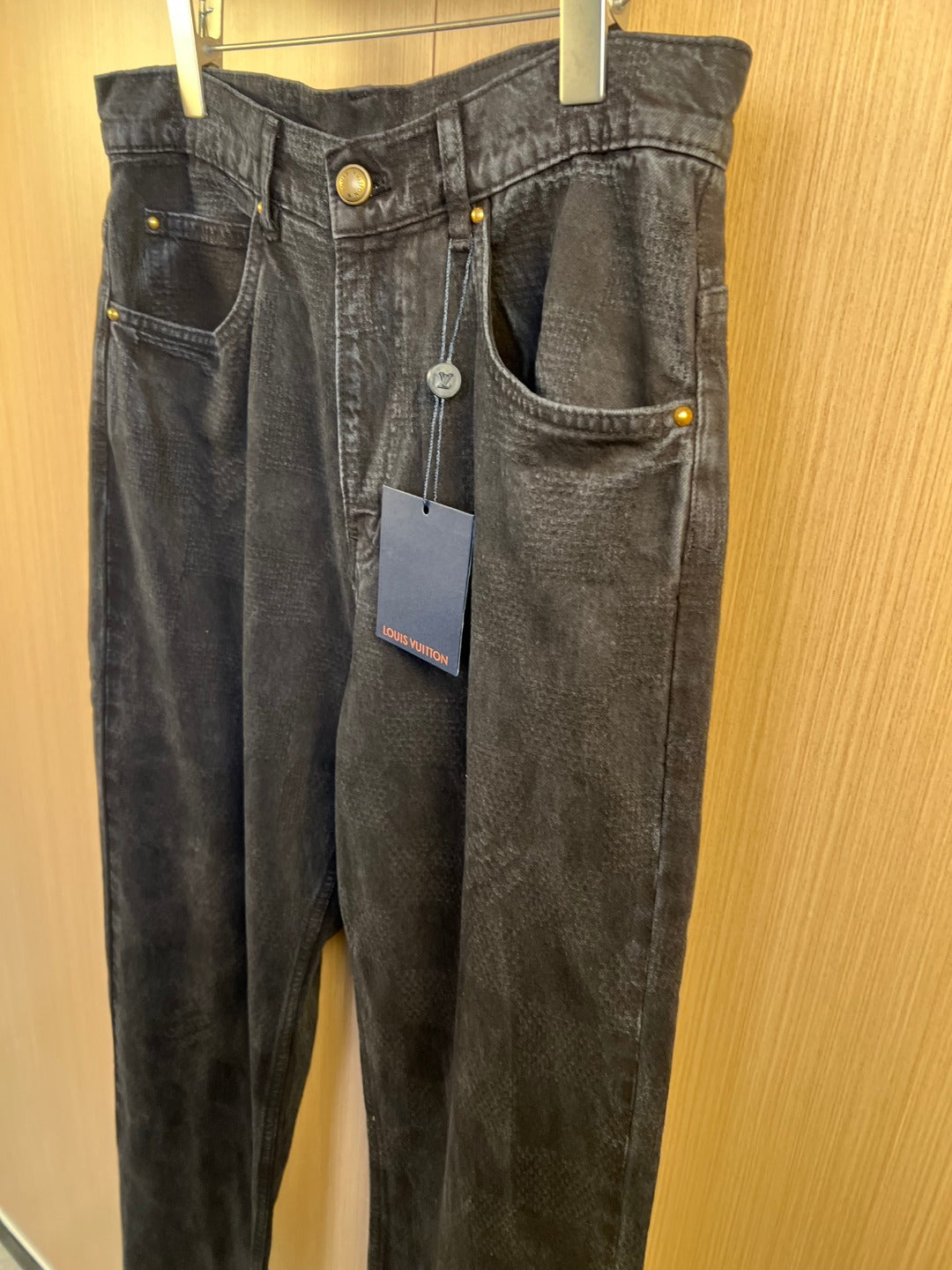Dark denim jeans on hanger with front pockets and button details