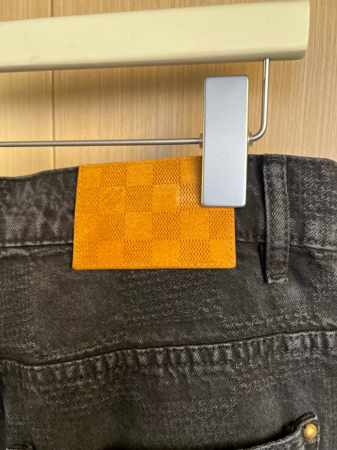 Dark denim jeans close-up of waistband pocket with orange brand tag