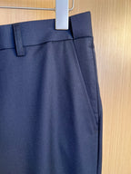Navy pants waistband with button closure and belt loops.