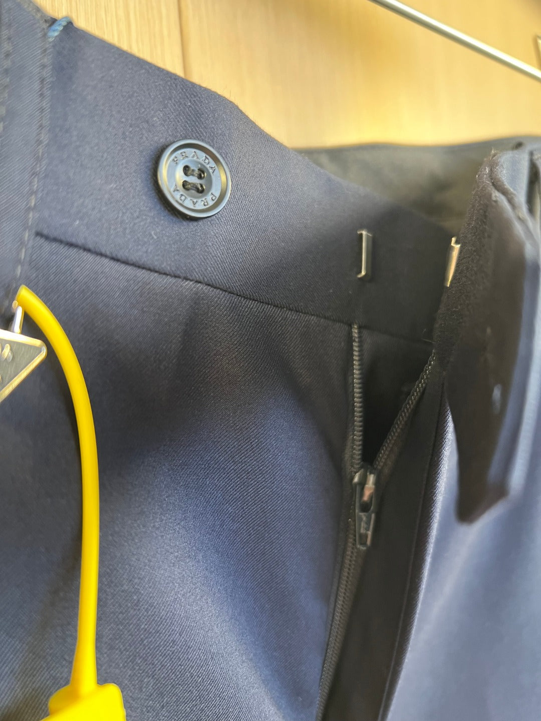 Navy pants side detail with belt loop, zipper fly, and embossed button.