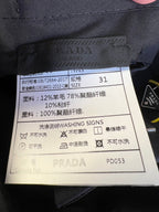 Prada fabric care label on navy pants with washing instructions.