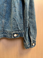 Denim jacket sleeve cuff with stitched hem and round metal button.