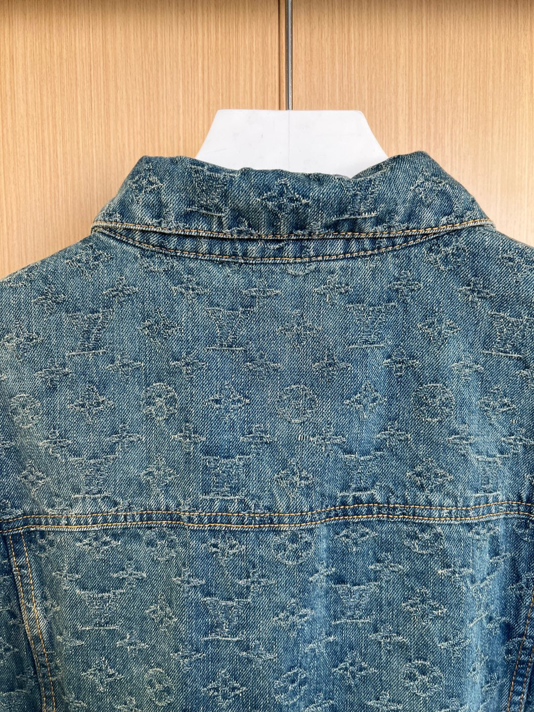 Denim jacket back yoke with pointed collar and stitched flap pocket details.
