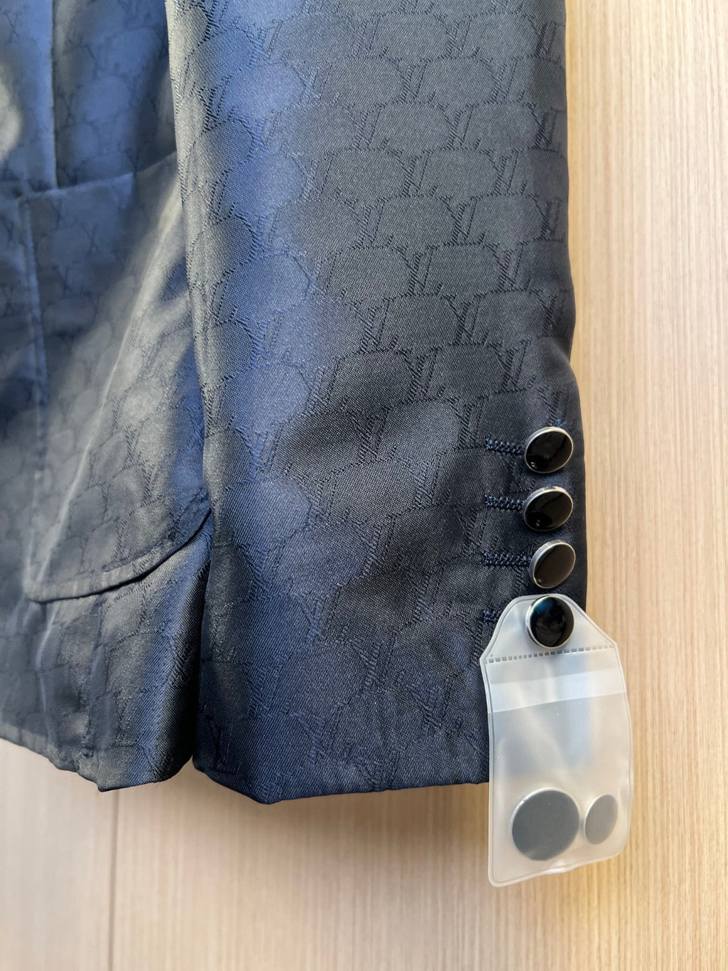 Dark navy blazer fabric close-up with embossed monogram pattern and round buttons