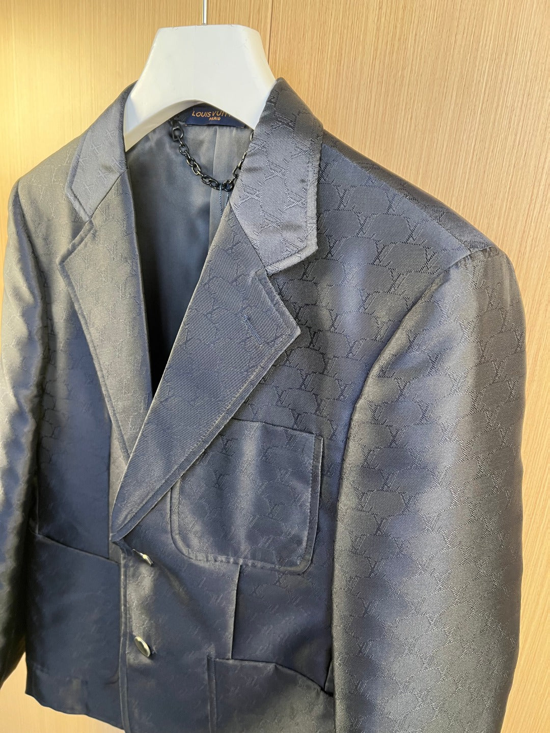 Dark navy blazer with lapels and welt pockets, monogram pattern, button closure