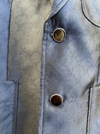 Dark navy blazer cuff close-up with embossed monogram texture and two gold-tone buttons