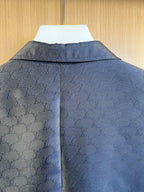 Dark navy blazer back close-up with embossed monogram pattern across shoulders