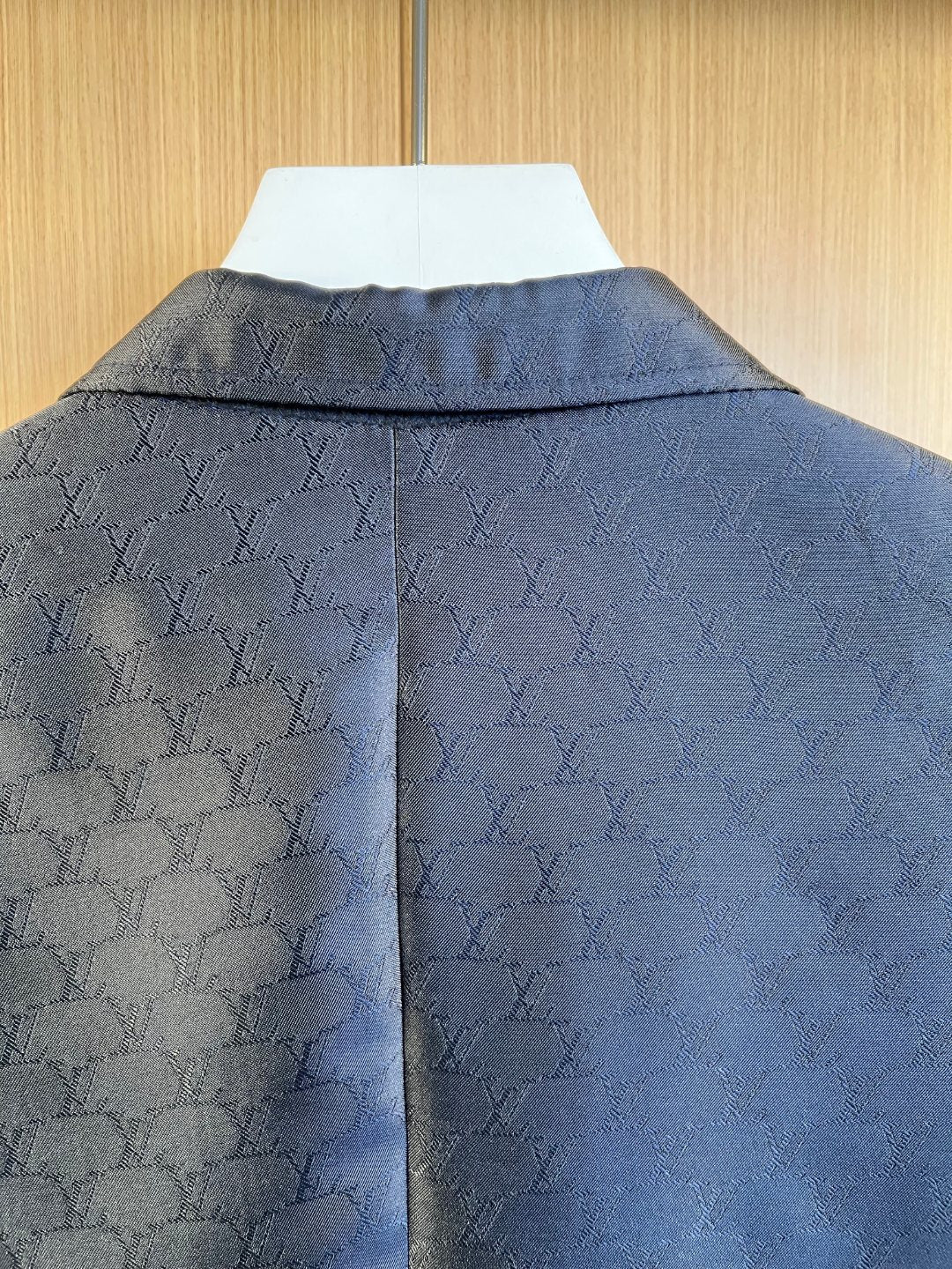 Dark navy blazer back close-up with embossed monogram pattern across shoulders