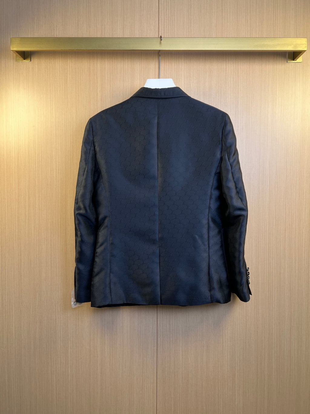 Dark navy blazer back view with center seam and lightly embossed monogram texture