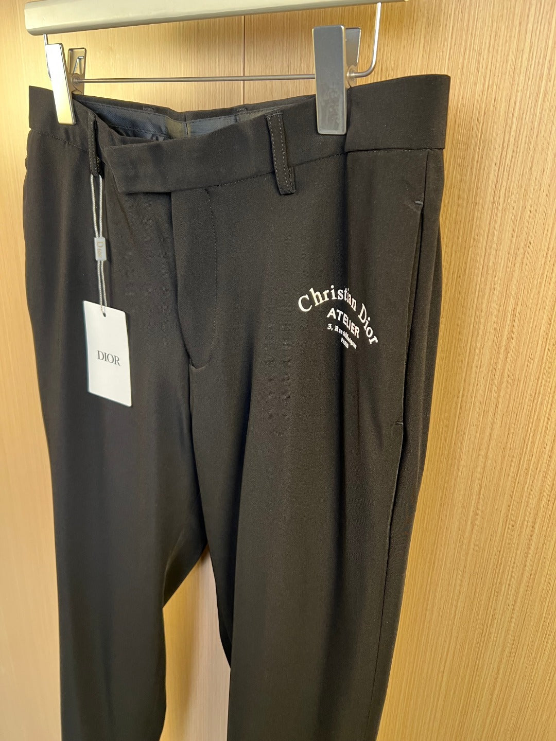 Dark pants with belt loops, front pockets, and Christian Dior Atelier logo