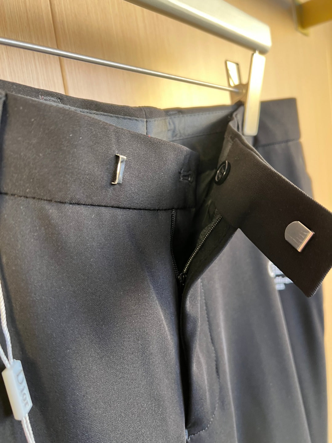 Dark pants waistband with belt loop, zipper fly, and button close-up
