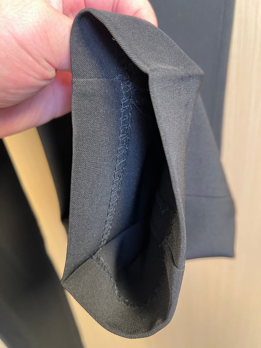 Dark pants fabric seam detail shown folded in hand