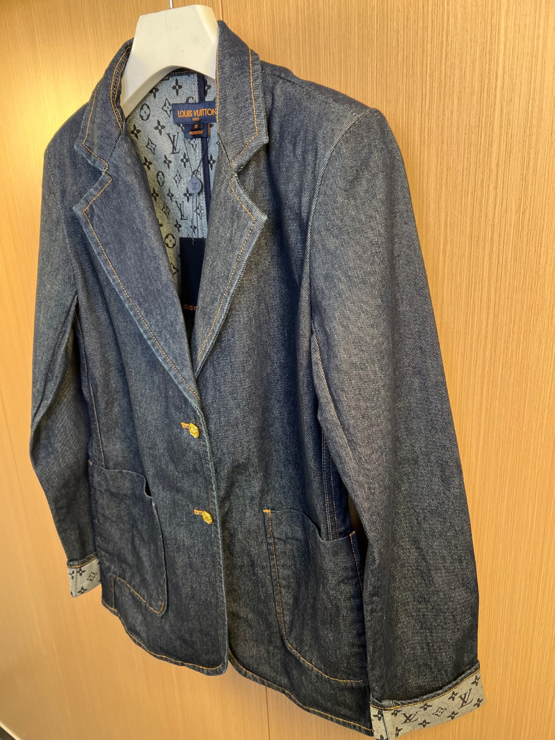 Dark blue denim jacket with interior monogram-style lining and gold button closure