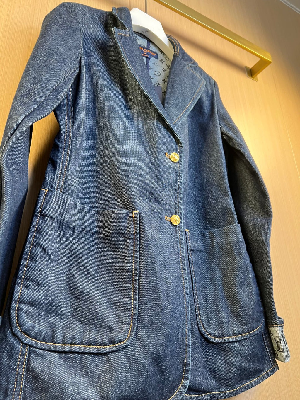 Dark blue denim jacket front detail with gold buttons and flap chest pockets