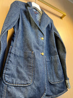 Dark blue denim jacket front detail with gold buttons and flap chest pockets