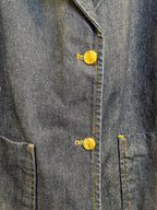 Denim jacket button detail with gold tone metal shank and embroidered emblem