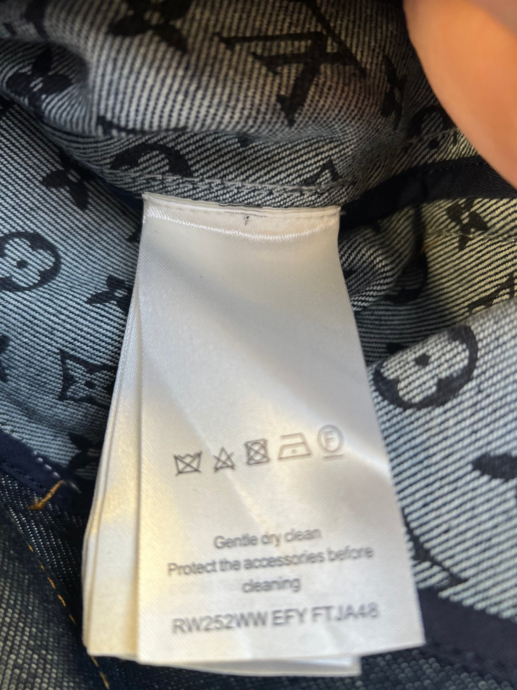 Denim jacket care label on inner tag with cleaning symbols and instructions