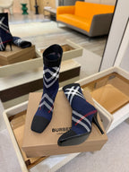Navy ankle boots with plaid shaft and stiletto heel, on display