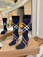 Pair of knee-high knit boots in navy with red and white check pattern and stiletto heels