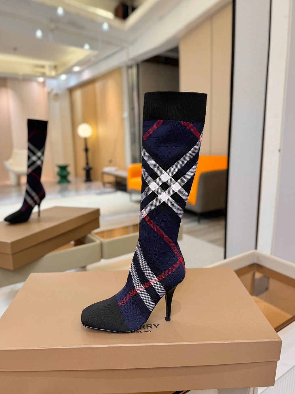 Knee-high knit boots with navy, red, and white check pattern and stiletto heel