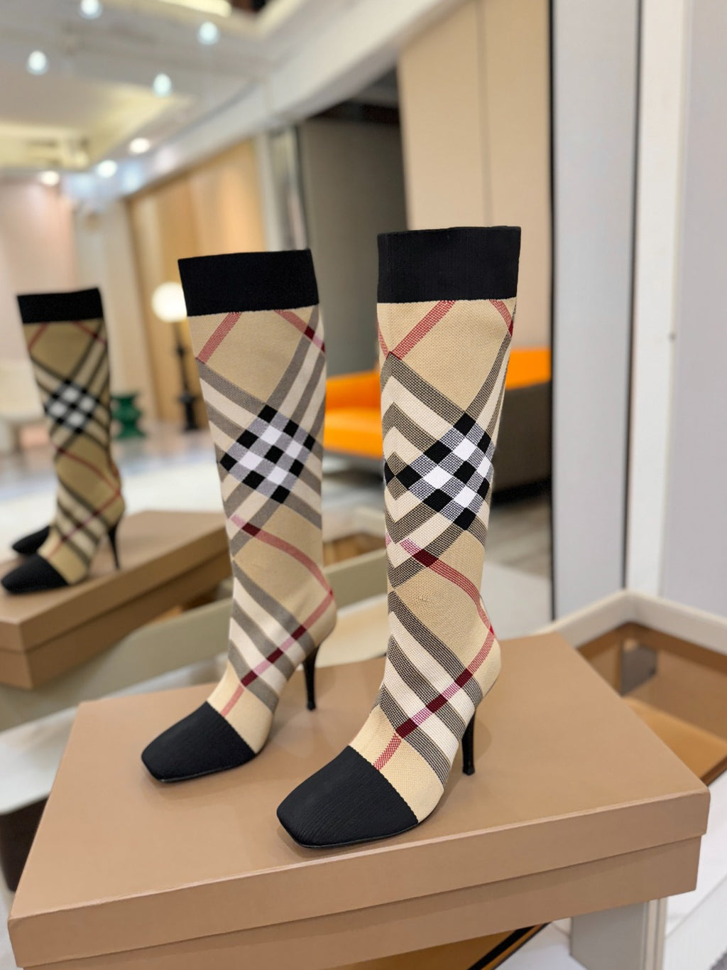Tartan sock-style knee-high boots on display, black cuffs, check pattern, high stiletto heels