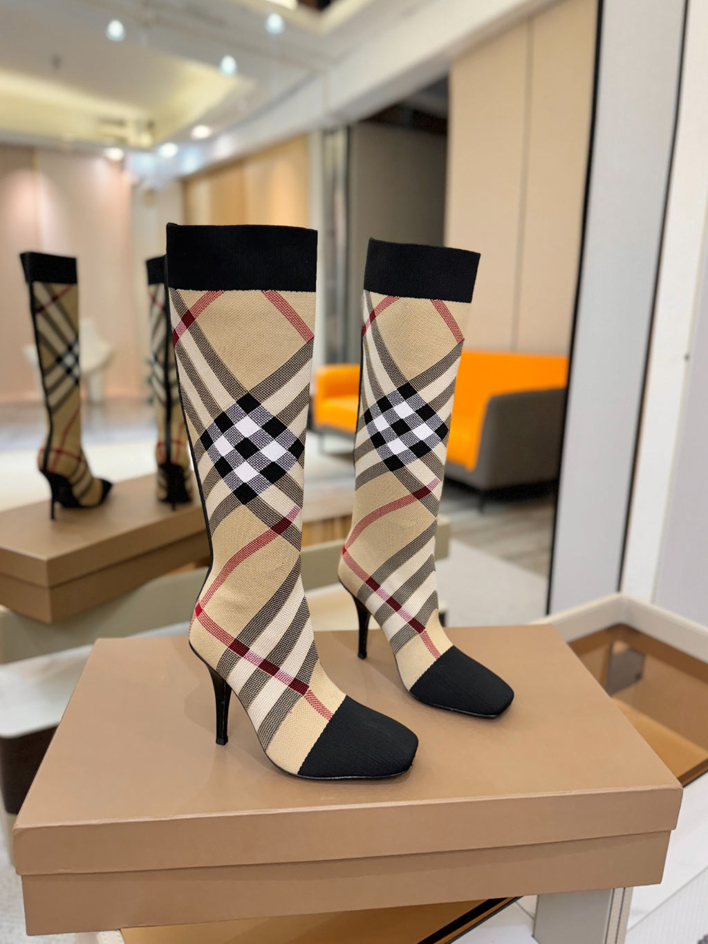 Pair of tartan sock-style knee-high boots with black cuffs and check panels, stiletto heels